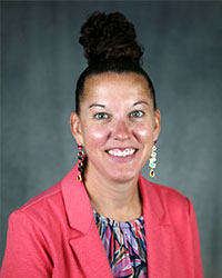 Drew Kenny Woman smiling wearing pink jacket and colorful top